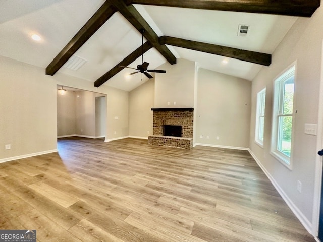 unfurnished living room featuring beam ceiling, a brick fireplace, hardwood / wood-style flooring, and ceiling fan