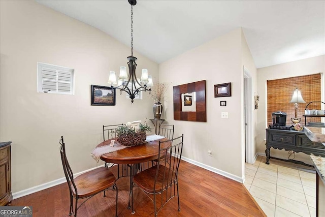 dining room with lofted ceiling, a notable chandelier, and light wood-type flooring