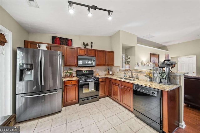 kitchen with sink, light tile patterned floors, kitchen peninsula, light stone countertops, and black appliances