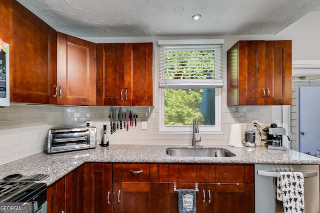 kitchen featuring sink, appliances with stainless steel finishes, light stone countertops, a textured ceiling, and backsplash