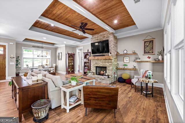 living room with ceiling fan, a raised ceiling, wooden ceiling, and a brick fireplace