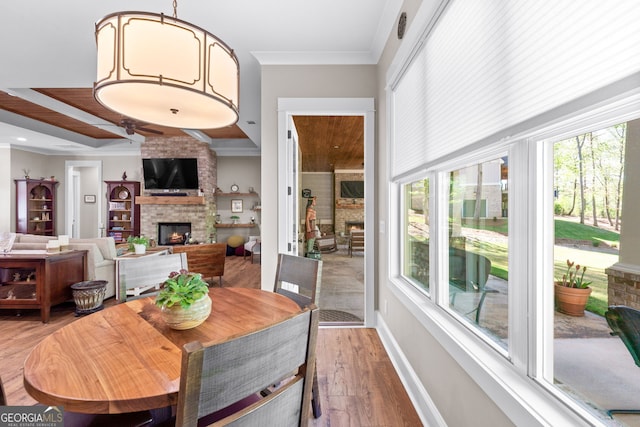 dining area with a large fireplace, hardwood / wood-style flooring, and crown molding