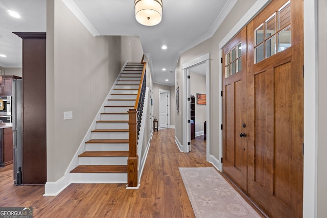 foyer entrance with wood-type flooring and ornamental molding