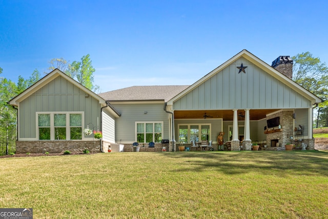 rear view of property with ceiling fan and a yard