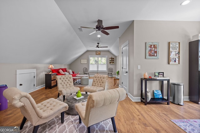 living room with ceiling fan, vaulted ceiling, and light wood-type flooring