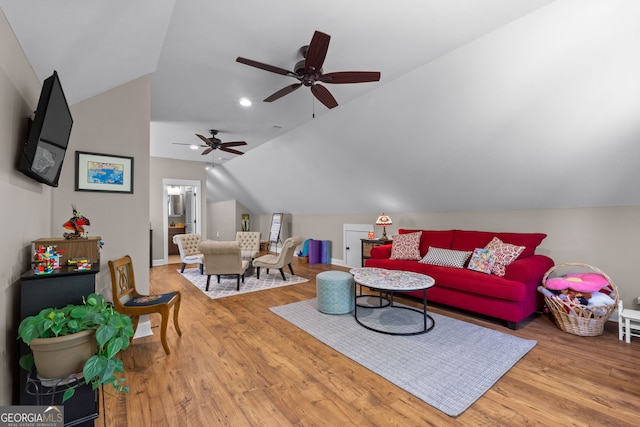 living room with hardwood / wood-style flooring, ceiling fan, and vaulted ceiling