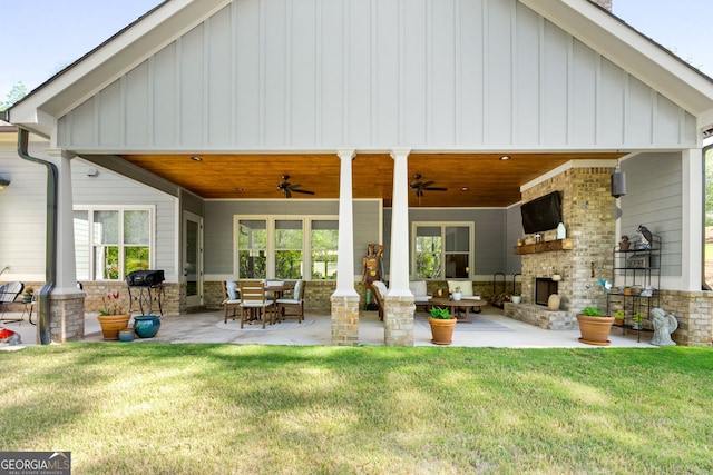 rear view of property featuring a lawn, ceiling fan, a fireplace, and a patio