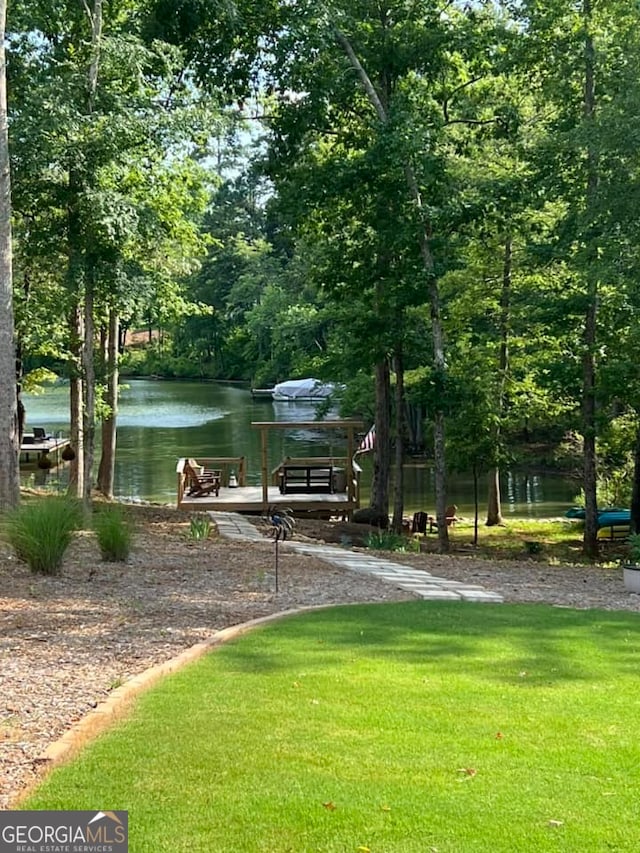 surrounding community with a water view and a lawn