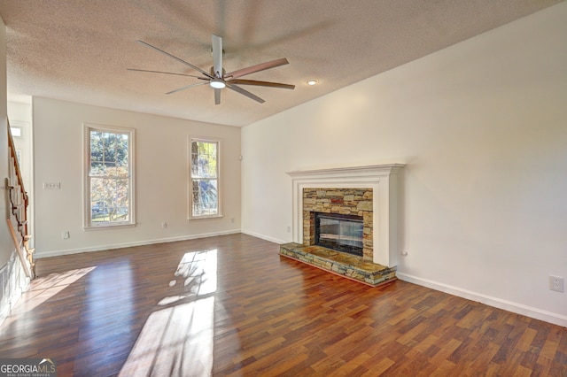 unfurnished living room with a textured ceiling, ceiling fan, a fireplace, and dark hardwood / wood-style flooring