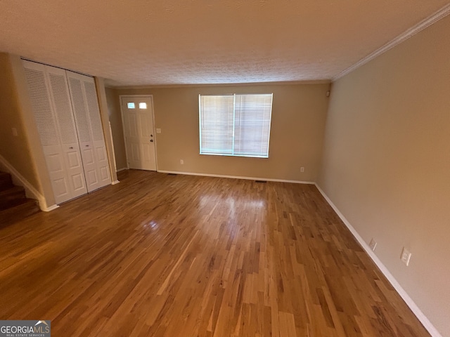 interior space with ornamental molding, a textured ceiling, hardwood / wood-style flooring, and a closet