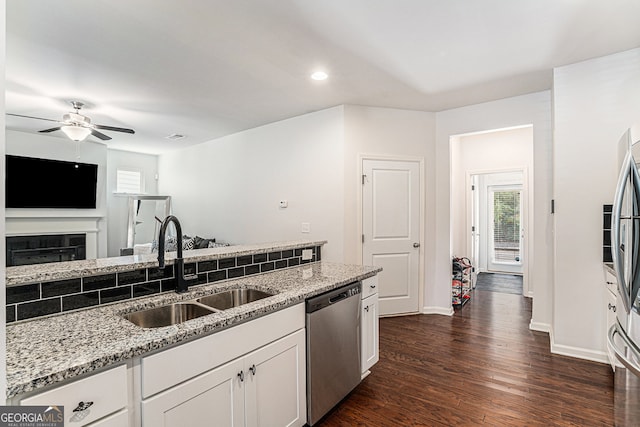 kitchen featuring sink, white cabinetry, stainless steel dishwasher, dark wood-type flooring, and light stone counters