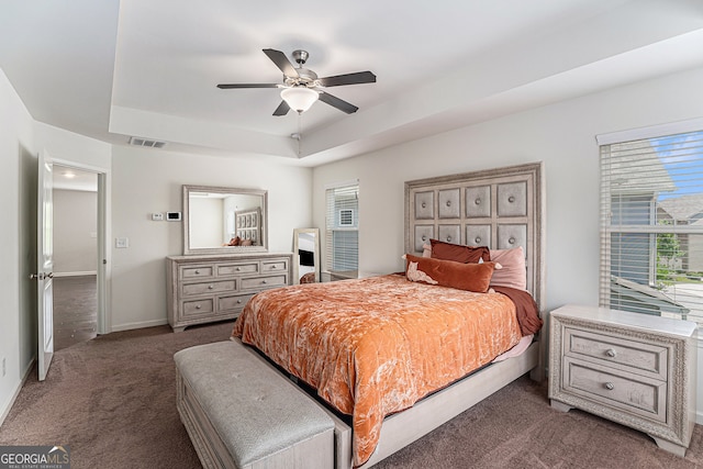 bedroom with dark carpet, a raised ceiling, and ceiling fan