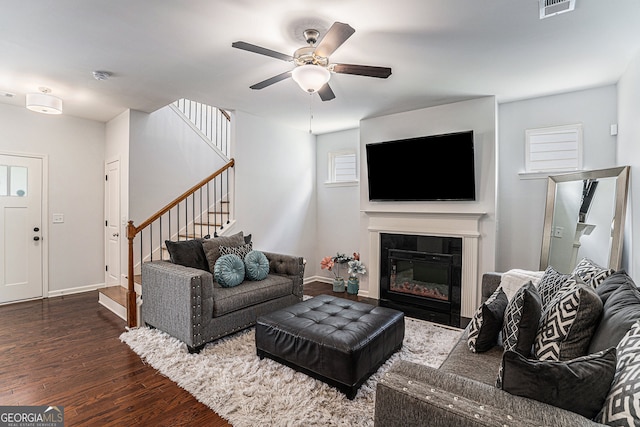 living room featuring dark wood-type flooring, a fireplace, and ceiling fan