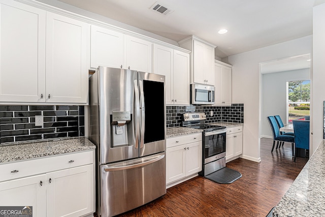 kitchen with appliances with stainless steel finishes, white cabinetry, light stone countertops, and dark hardwood / wood-style flooring