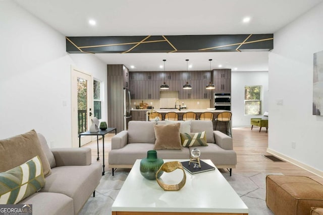 living room with a healthy amount of sunlight, sink, and light wood-type flooring