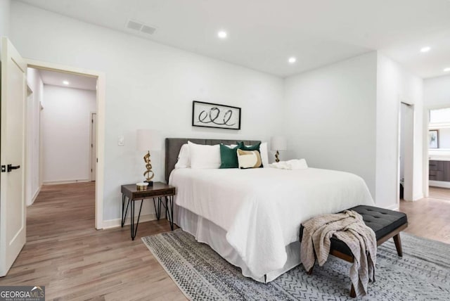 bedroom with connected bathroom and light hardwood / wood-style floors