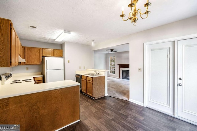 kitchen featuring dark wood-type flooring, kitchen peninsula, decorative light fixtures, a textured ceiling, and white appliances