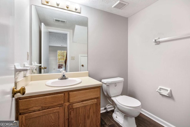 bathroom featuring toilet, a textured ceiling, hardwood / wood-style flooring, and vanity