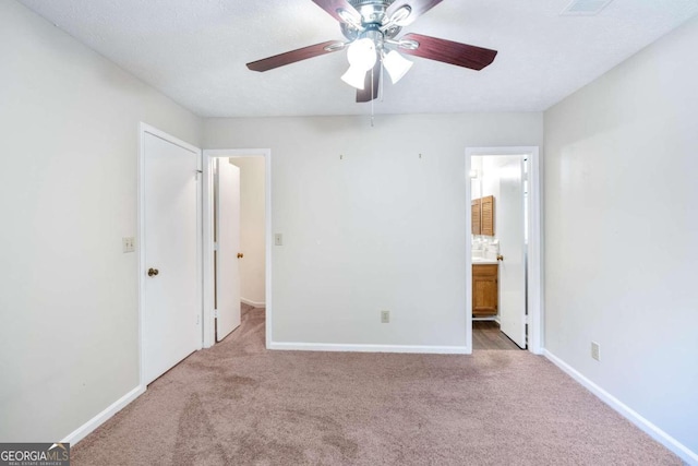 unfurnished bedroom with ensuite bath, a textured ceiling, carpet floors, and ceiling fan