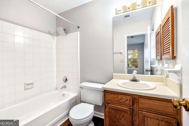 full bathroom featuring tiled shower / bath, vanity, a textured ceiling, and toilet