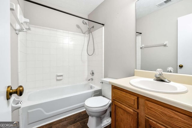 full bathroom with toilet, wood-type flooring, tiled shower / bath, vanity, and a textured ceiling