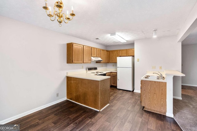 kitchen featuring kitchen peninsula, hanging light fixtures, a textured ceiling, dark wood-type flooring, and white appliances