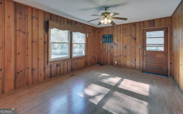 interior space featuring hardwood / wood-style flooring, ceiling fan, wooden walls, and a wealth of natural light