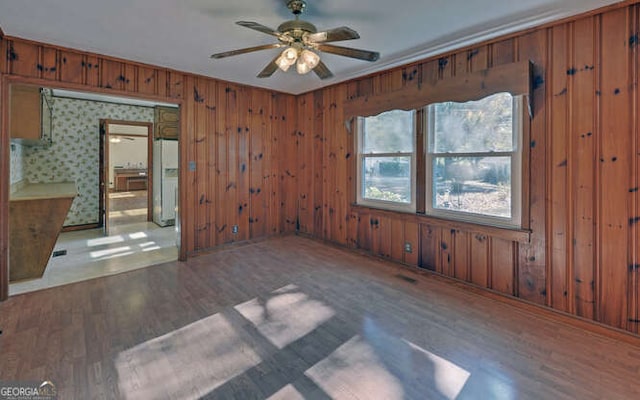 spare room with hardwood / wood-style flooring, ceiling fan, and wooden walls