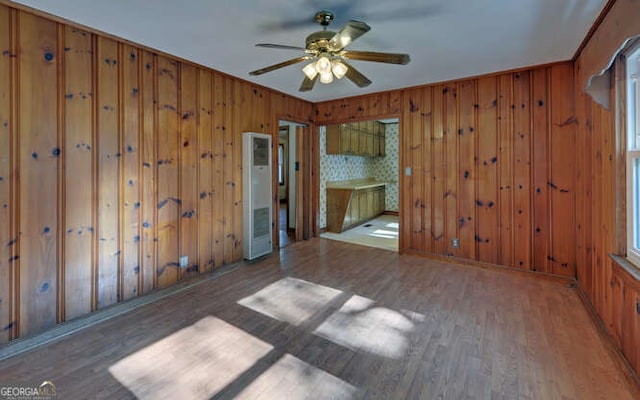 unfurnished room featuring ceiling fan, wood walls, dark hardwood / wood-style flooring, and plenty of natural light