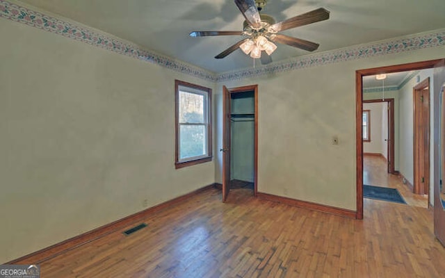 unfurnished bedroom with ceiling fan, a closet, wood-type flooring, and ornamental molding