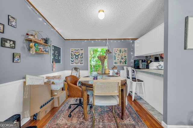 dining space with crown molding, a textured ceiling, and light hardwood / wood-style flooring