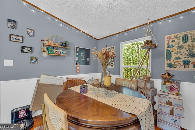 dining room featuring vaulted ceiling, a textured ceiling, and hardwood / wood-style flooring