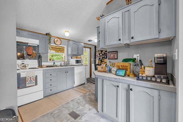 kitchen with tile countertops, premium range hood, a textured ceiling, and white appliances