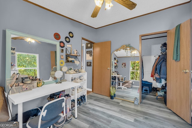 interior space with ornamental molding, a textured ceiling, light wood-type flooring, and ceiling fan