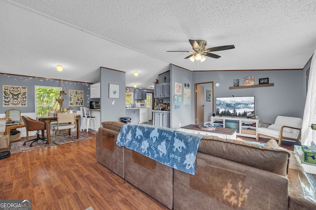 living room featuring dark wood-type flooring, ornamental molding, vaulted ceiling, a textured ceiling, and ceiling fan