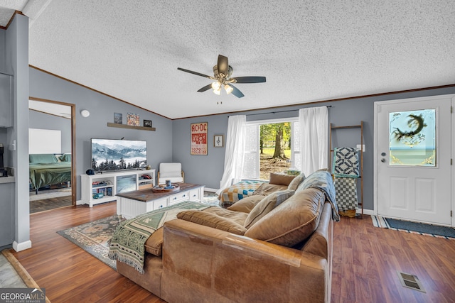 living room with wood-type flooring, a textured ceiling, ceiling fan, vaulted ceiling, and crown molding