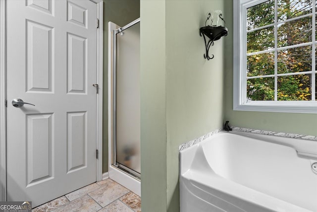 bathroom with a stall shower, a garden tub, and stone tile flooring