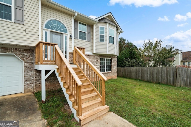 view of exterior entry featuring a yard, brick siding, and fence