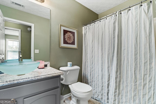 full bathroom featuring visible vents, toilet, a textured ceiling, vanity, and baseboards