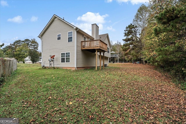 back of house with a chimney, fence, a deck, and a yard