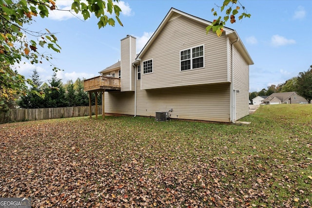 rear view of property featuring central AC unit, a chimney, fence, and a lawn