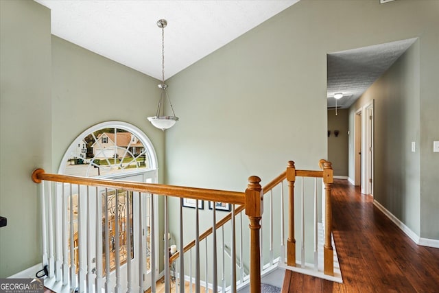 corridor with attic access, a textured ceiling, an upstairs landing, wood finished floors, and baseboards