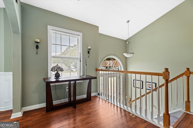 corridor featuring baseboards, vaulted ceiling, and wood finished floors