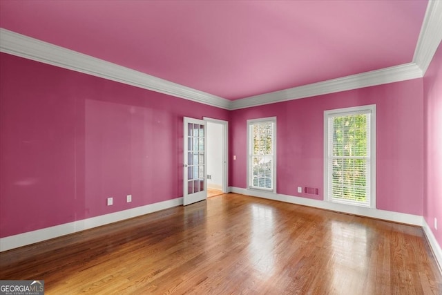 unfurnished room featuring baseboards, visible vents, ornamental molding, wood finished floors, and french doors