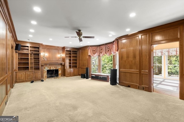 unfurnished living room with wooden walls, recessed lighting, light colored carpet, a fireplace, and crown molding