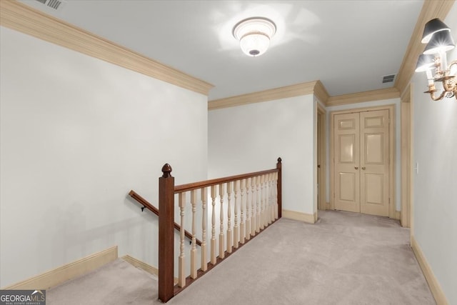 hallway with carpet, visible vents, ornamental molding, and an upstairs landing