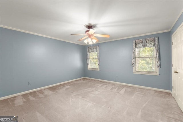 carpeted spare room featuring ceiling fan, baseboards, and crown molding