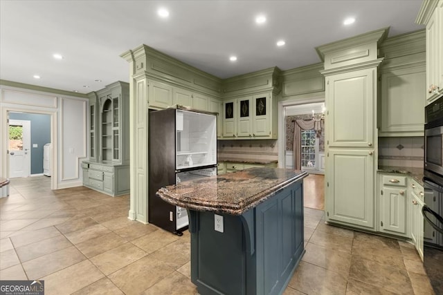 kitchen with recessed lighting, a kitchen island, freestanding refrigerator, dark stone countertops, and green cabinetry