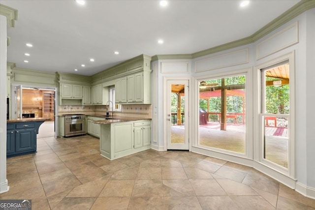 kitchen featuring a peninsula, a sink, stainless steel range oven, tasteful backsplash, and crown molding