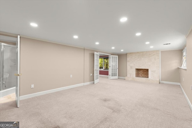 unfurnished living room with baseboards, crown molding, french doors, a fireplace, and recessed lighting